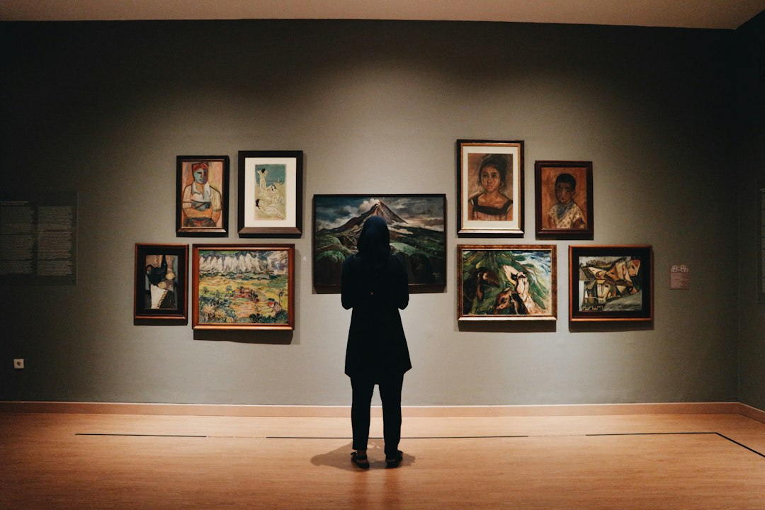 A visitor viewing large, immersive paintings in a brightly lit virtual art gallery exhibition space
